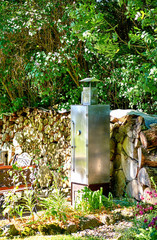 Metal smokehouse for fish and meat in a garden.