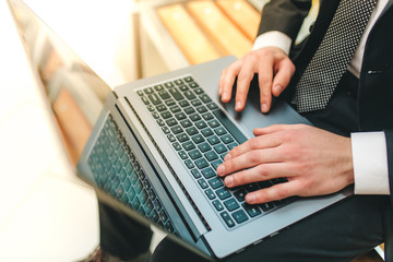 Cropped image view of man's hands in elegant suit keyboarding on laptop computer with blank copy space screen for your advertising content or text message, man working on net-book in a cafe,