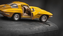 Toy Car Model Corvette Sting Ray 1963 Year. Yellow Color. Side View. Opened Door. Close-up. Macro. Isolated.
