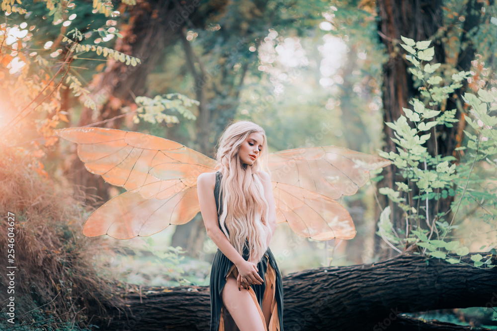 real fairy from magical stories, goddess of nature with transparent wings alone in dense forest, beauty closes her eyes, listens to birds singing, charming lady in the sunlight and with bare legs - obrazy, fototapety, plakaty 