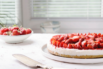 Wall Mural - Strawberry cheesecake on white table near window. Selective focus