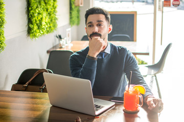 Wall Mural - Pensive businessman sitting in front of laptop in the cafe