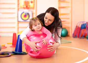 mom and baby having fun with gymnastic ball in gym