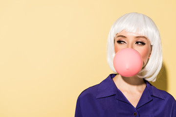 Wall Mural - Girl in white wig chewing bubble gum on yellow background