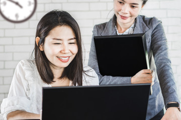 two happy Asian business woman working together looking at computer screen ,teamwork concept background 