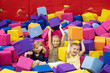 Little smiling blond girls sitting in the playroom and joyfully playing with colorful soft cubes