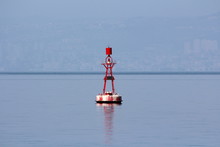 Small Red Navigational Buoy With Light On Top And Solar Panels For Charging Surrounded With Calm Blue Sea On Warm Spring Day