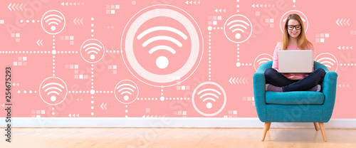Foto Wifi concept with young woman using her laptop in a chair