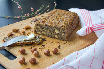 Fresh homemade keto bread with almonds, hazelnuts, sunflower seeds, chia seeds on a wooden cutting board