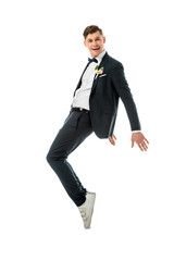 Wall Mural - cheerful groom dancing in black suit and white sneakers isolated on white