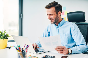 Happy businessman working with financail documents at office