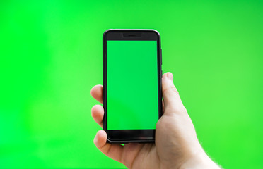 Male hand with Smartphone over green screen. Place for your advertisement.