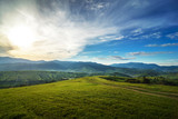 Fototapeta Góry - Meadows with horses, a village and a view of the mountains (Ukrainian Carpathians). Sunset landscape with beautiful clouds