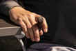 © Susan Vineyard  - Close-up of man's hand resting on side of table beside his chair holding a lit cigar