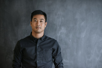 Wall Mural - Confident Asian businessman standing in front of a blank chalkboard