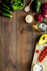 Wall Mural - Ingredients for fresh vegetable salad and cutting board on dark wooden kitchen desk top view copy space