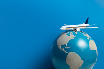 white airplane toy model with global world on blue background in airline business for travel tour international concept