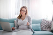 © leszekglasner - Pregnant woman working online with laptop at home, freelancing concept
