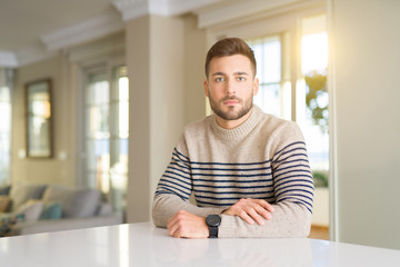 Wall Mural - Young handsome man at home Relaxed with serious expression on face. Simple and natural looking at the camera.