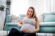 © leszekglasner - Beautiful smiling pregnant woman sitting on floor at home, looking at camera