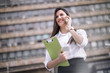 © Visual Intermezzo - Young business woman speaking on cell phone outdoor
