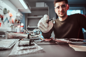 Wall Mural - Master of electronic technology holds chip of broken tablet in the repair shop