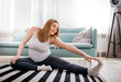 © leszekglasner - Beautiful pregnant woman doing exercise at home in living room, health during pregnancy