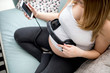 © leszekglasner - Beautiful cheerful pregnant woman holding headphones on belly showing music to baby