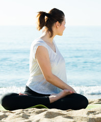 Wall Mural - Adult woman in white T-shirt is practicing stretching