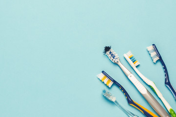 Wall Mural - Several different used toothbrushes on a blue background. Toothbrush change concept, oral hygiene, big and friendly family. Flat lay, top view.