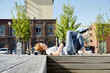 © Westend61 - Smiling young woman with longboard lying on bench in urban surrounding