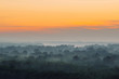 © Daniil - Mystical view from top on forest under haze at early morning. Mist among layers from tree silhouettes in taiga under warm predawn sky. Morning atmospheric minimalistic landscape of majestic nature.