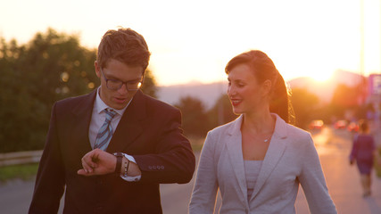 Wall Mural - CLOSE UP: Young businessman checks his watch while talking to female colleague.