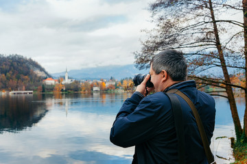 Wall Mural - Man taking photos of Bled Lake and Church in Slovenia