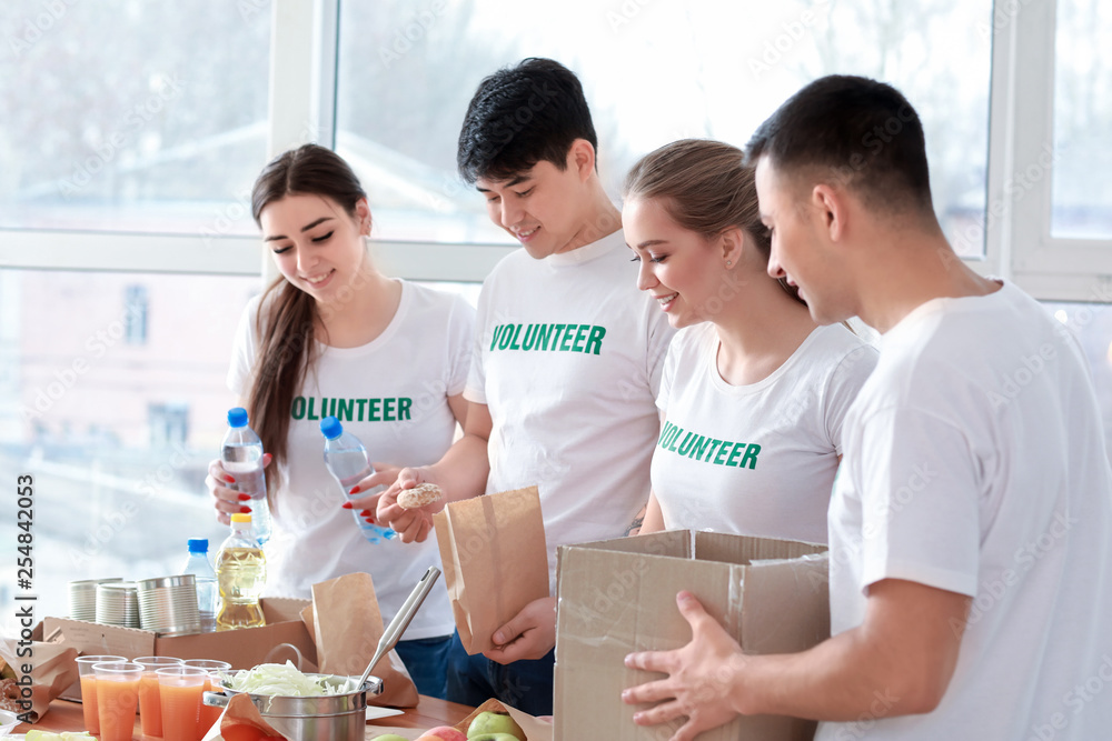 Young volunteers with food for poor people indoors