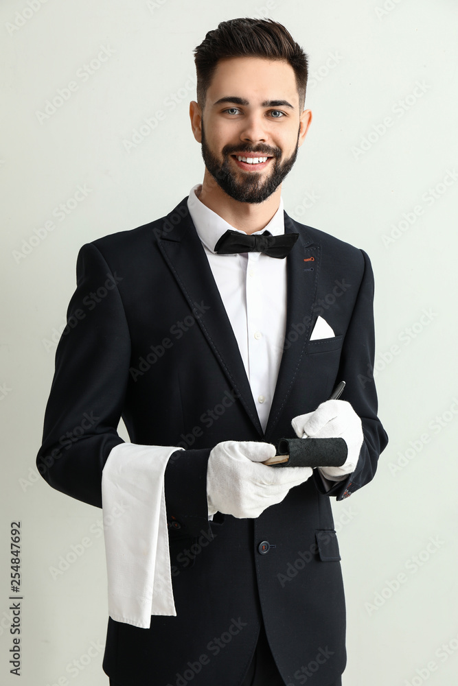 Waiter with notebook on light background