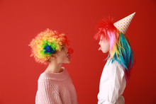 Woman And Little Girl In Funny Disguise On Color Background. April Fools' Day Celebration
