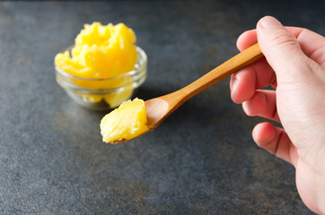 Wooden spoon with organic and homemade ghee butter for cooking healthy meal. Healthy ingredients on your kitchen