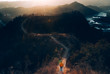 © kintarapong - Woman hiking on mountain path into the wild at sunset or sunrise above mountains- traveling adventure- lifestyle- outdoor activity and nature adventure concept