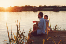 Young Loving Couple Enjoys By The River During The Sunset
