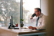 © Jacob Lund - Doctor working at his office desk and drinking coffee