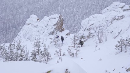 Wall Mural - A group of tourists with backpacks on their shoulders descends from the top of a snow-covered mountain. Slow motion.