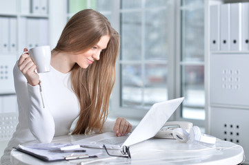 Portrait of young woman working at office, using laptop