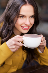 Sticker - drinks and people concept - happy young woman or teenage girl drinking f hot chocolate at city street cafe terrace