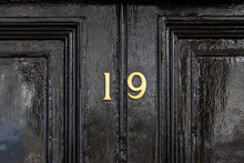HOuse Number Nineteen With The 19 In Bronze On A Black Wooden Panel Door