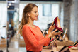 sale, shopping, fashion and people concept - happy young woman choosing shoes at store