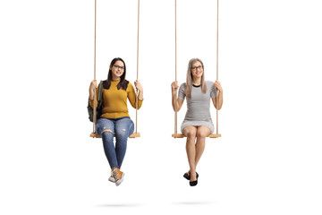 Wall Mural - Two young women sitting on a swing and smiling at the camera