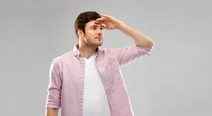 new beginnings and people and concept - happy young man looking far over grey background