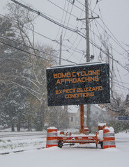 Wall Mural - Electric road traffic mobile sign by the side of a snow covered road with snow falling warning of BOMB CYCLONE approaching, expect blizzard conditions