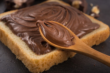 Wall Mural - Chocolate spread on slice of bread with spoon, melted cream white bowl